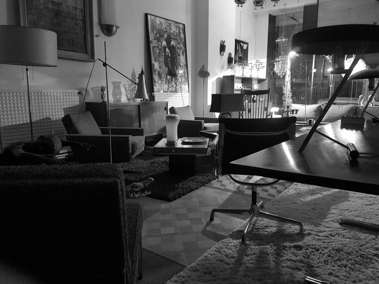 Même salon de la boutique en noir et blanc, fauteuils, luminaires et parquet.