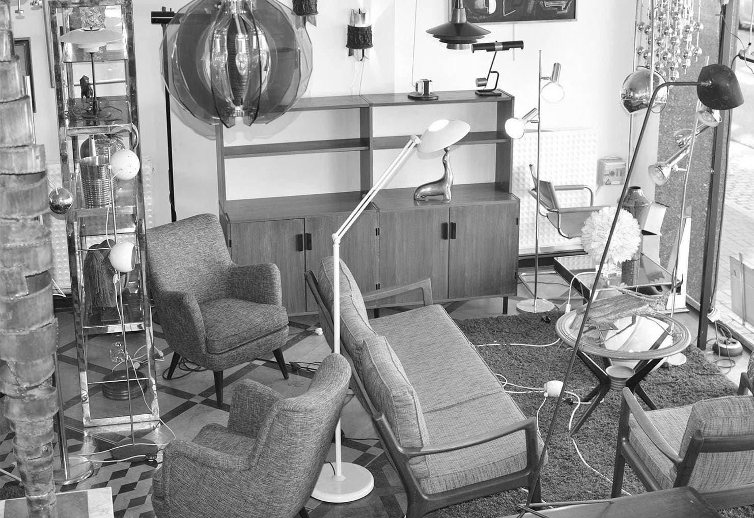 Vue plus large du showroom : sièges vintage, luminaires et sol géométrique.
